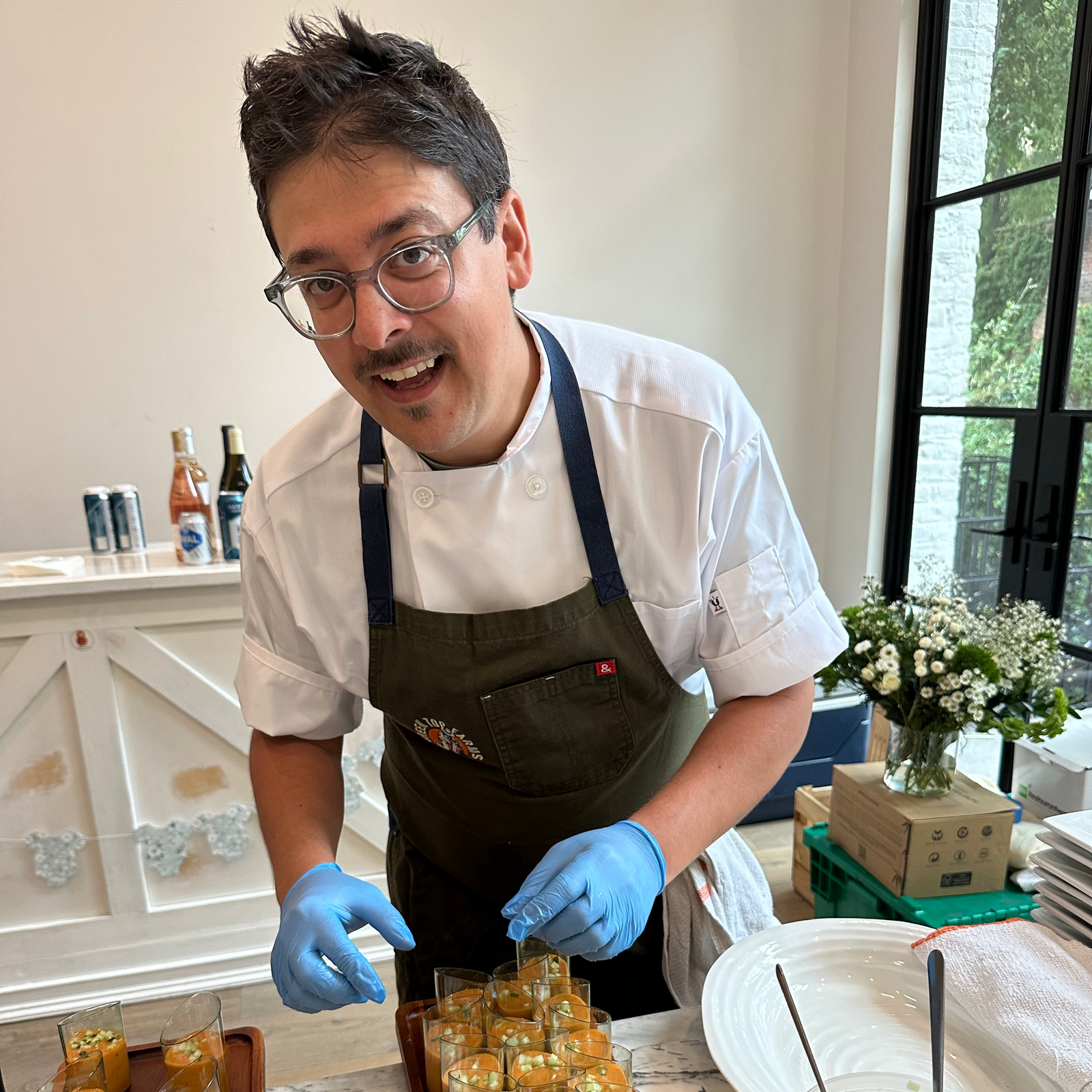 Chef preparing small appetizers on a wooden tray in a kitchen setting.